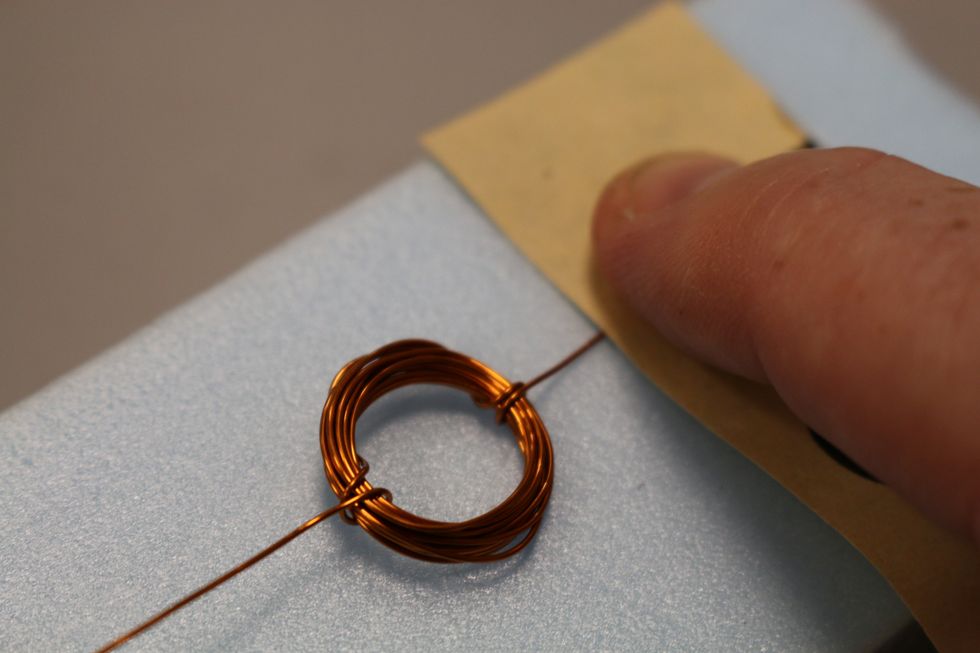 Lay your coil flat and sand just one side (right) of one end of wire and then sand the other (left) wire end. Be sure the sanding happens only on one side of the two wire ends.