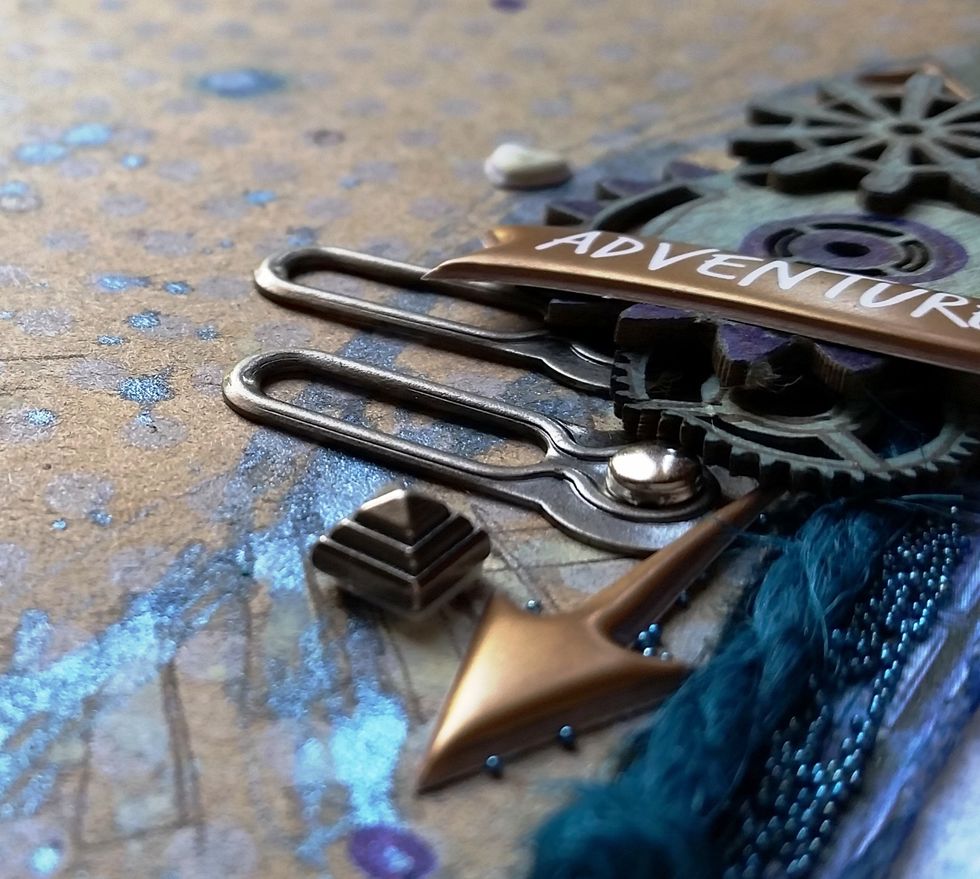 Layer in your pictures, chipboard, 7 Gypsies metals, and Paper House stickers as seen using the Tombow Xtreme Permanent Adhesive, Glue Dots, and Stamp Runner.