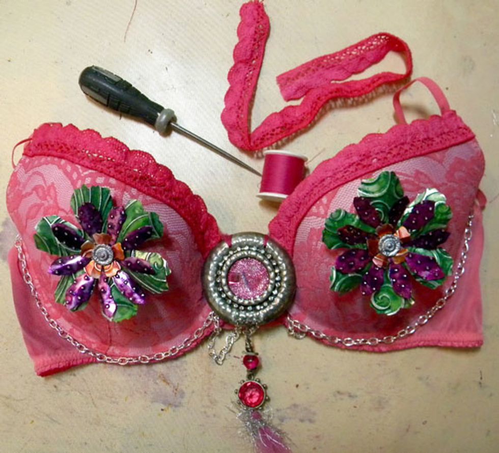 Layer the flowers and secure to the bra with a silver brad. I made a hole in the bra first with the piercer tool. Hand sew the pink lace, pendant and silver chain onto the bra.