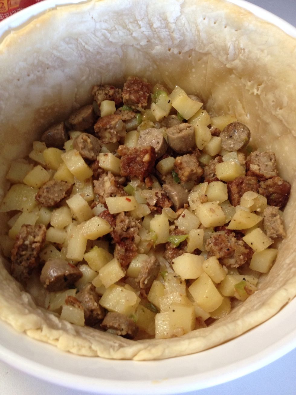 Layer the sausage and potatoes in the dish.