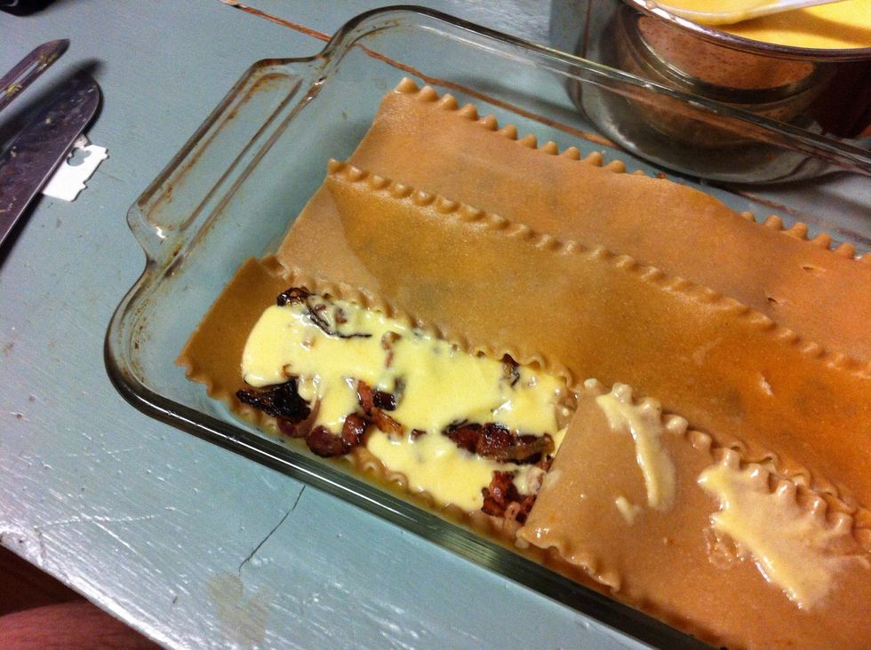 Layer with noodles, shallots and bacon, cheese sauce and another layer of noodles