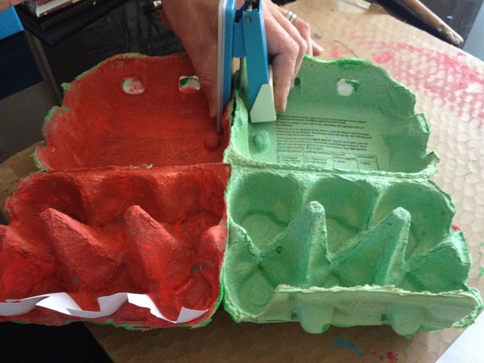 Leg de eierdozen in de lengte tegen elkaar en niet ze vast. Knip de 2 rode helften los van elkaar