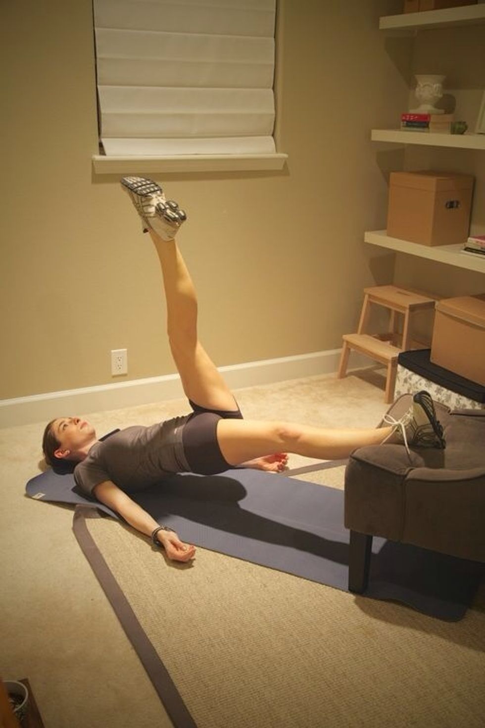 Leg Lifts with Chair: Place feet in the seat of a chair and lift torso off the ground. Alternate lifting the left and right legs into the air for 1 minute.