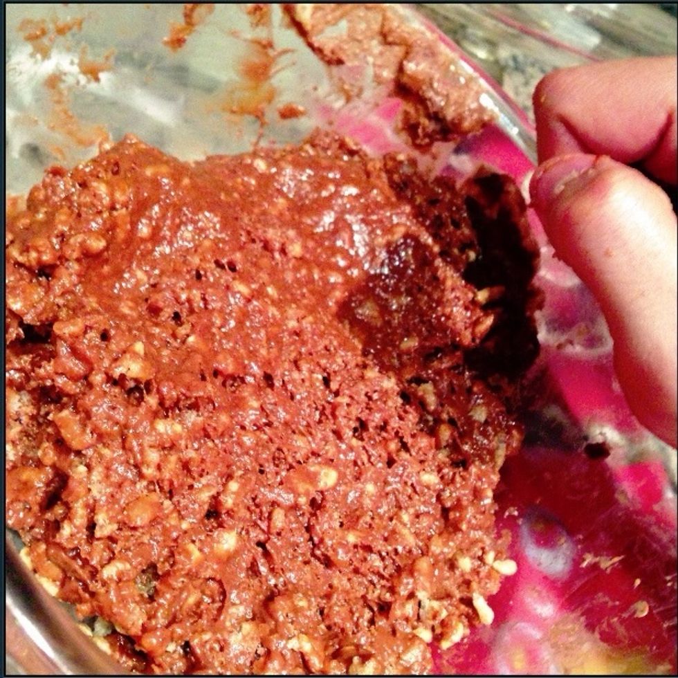 Let go of your spoon. It's time to get down and dirty with your creation. Start mixing with your hand. You'll notice mixing is more effective here. The Rice Krispies settle into a brown-gold color.