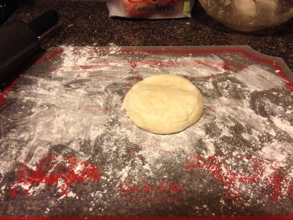 Let's roll out the first one! Lay down some flour so your ball doesn't get stuck to the surface. Use a rolling pin to roll out the crust.