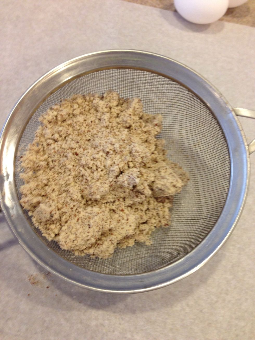 Let's start with the dry. Sift your almond flour onto parchment to make sure it's not clumpy. It's incredibly important to do these steps because macarons are very light fluffy delicate cookie wafers.