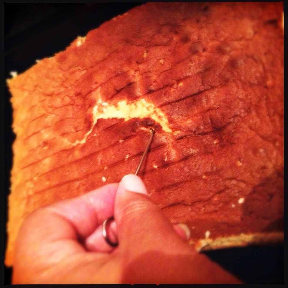 Let the cake cool and turn out unto a cutting board. Gently trim the sides and place back in the tin upside down. Then pierce all over with a fork or skewer.