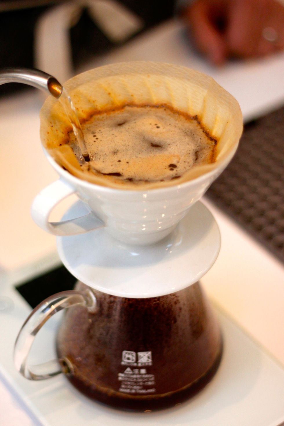 Let the second pour start to drain. Before you can see the beans again, pour in more water so the total weight is 300 grams. Make sure to continue the circular pouring, avoiding the very edge.