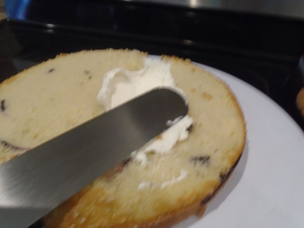 Level the other cake then spread frosting on the cake using your offset spatula. This will be the crumb coat. The crumb coat catches all the crumbs so it doesn't get in the frosting.