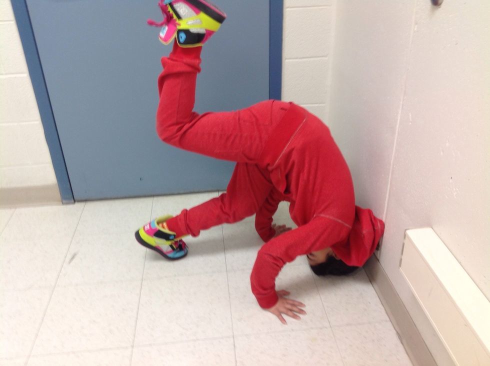 Lift one foot up off the floor. This will cause your head to roll forwards so that the top of your head will be on the floor.