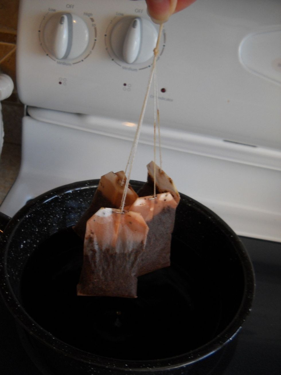 Lift out the tea bags, squeeze the tea into the pot and discard the bags.