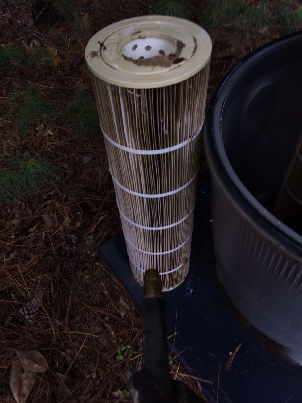 Lift the first filter out place it next to the filter assembly and start to hose it down using a gentle hose spray. Work from top to bottom until you see clear water running out at the bottom