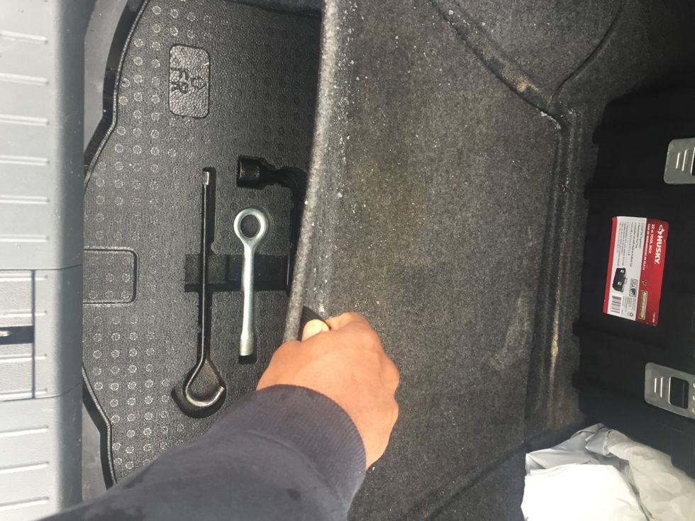 Lift the floor of the vehicles trunk to locate the spare tire. In some cars you will find the necessary tools on top of the tire as pictures above.