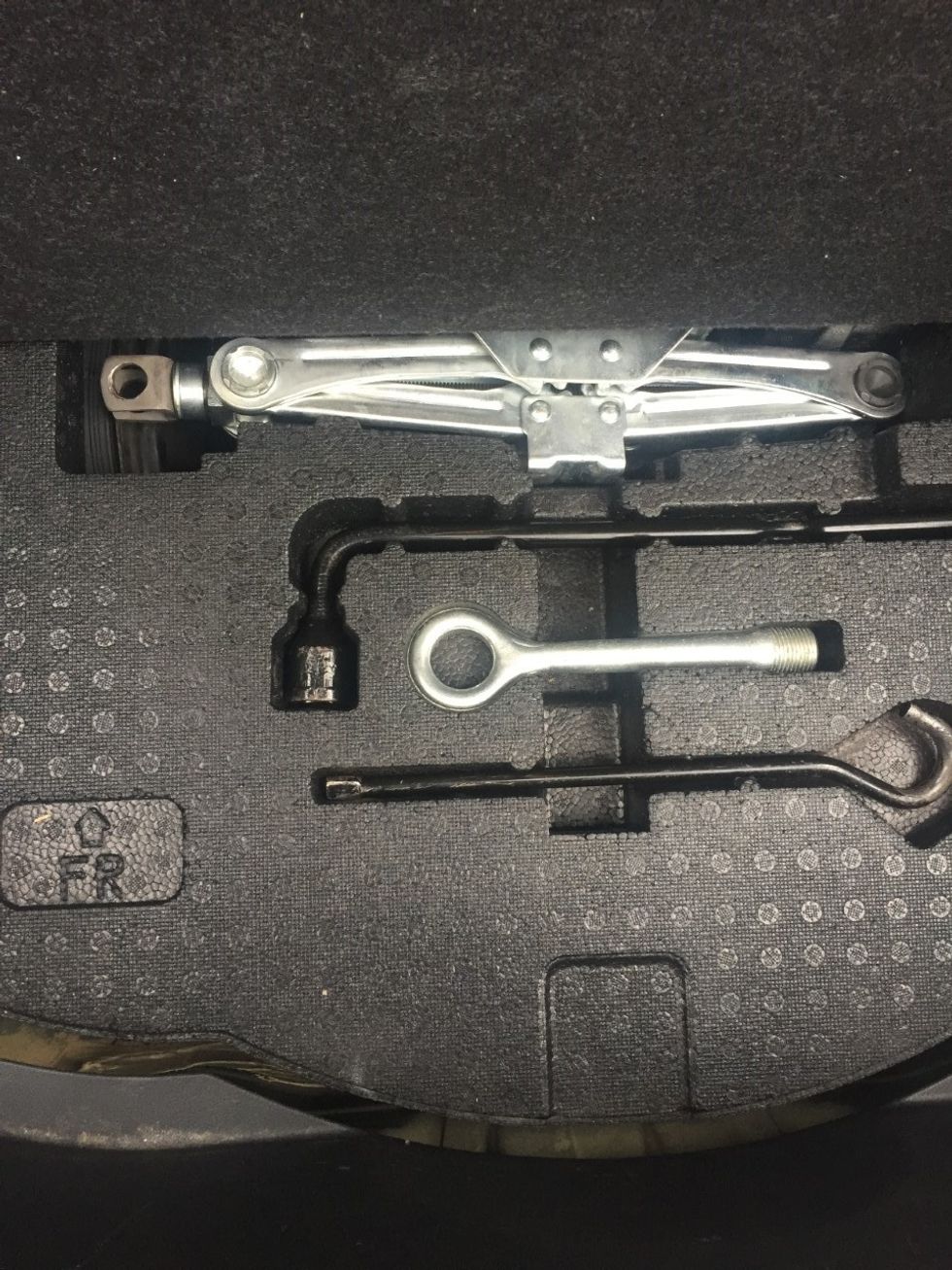 Lift the foam housing the tools to get to your tire. Keep in mind the tire will be low causing you to bend over the opening of the trunk. Be sure to exercise caution as to no injure your back.