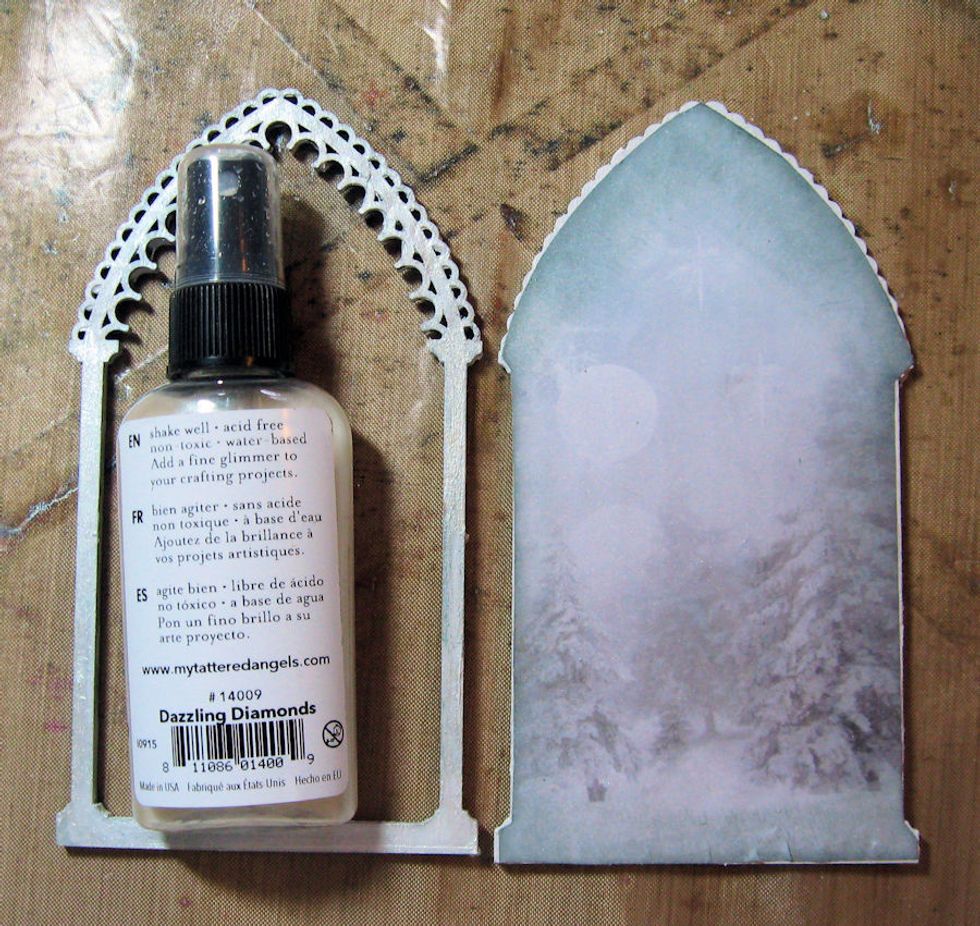 Lightly mist the paper with Dazzling Diamonds Mist. Spray a heavy coat of the mist on the top of the frame.  Dry with a heat tool. Spray the tree and the chipboard snowflakes at the same time.