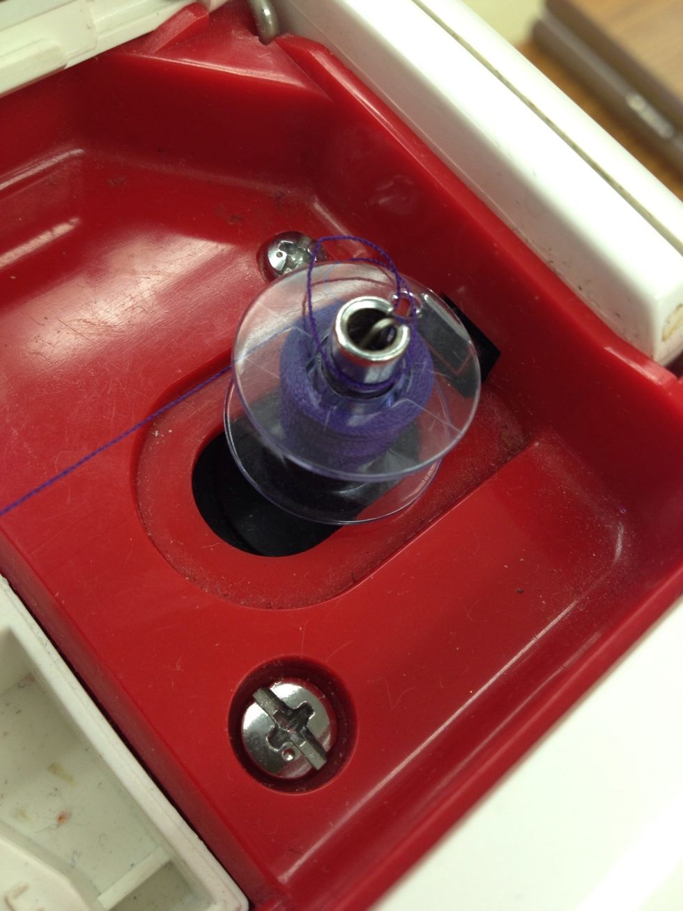 Lightly push on the foot pedal to wind the thread around the bobbin.