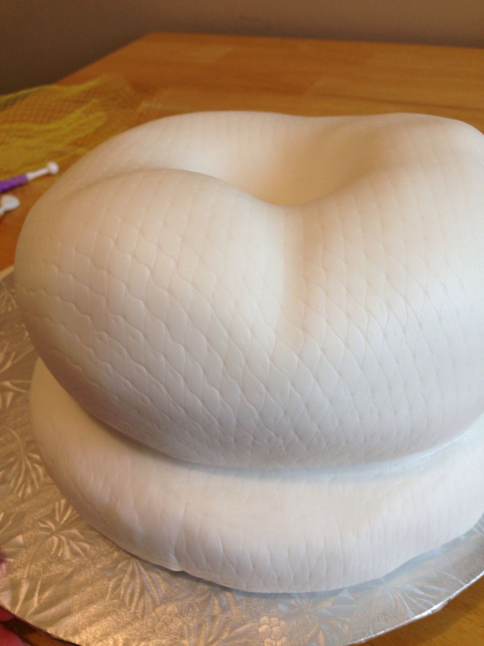 Lightly spritz the ganached cake with a mist of water, and put your fondant over the cake, carefully pressing it into the "snake coils" and any crevices you've created to add definition to your cake.