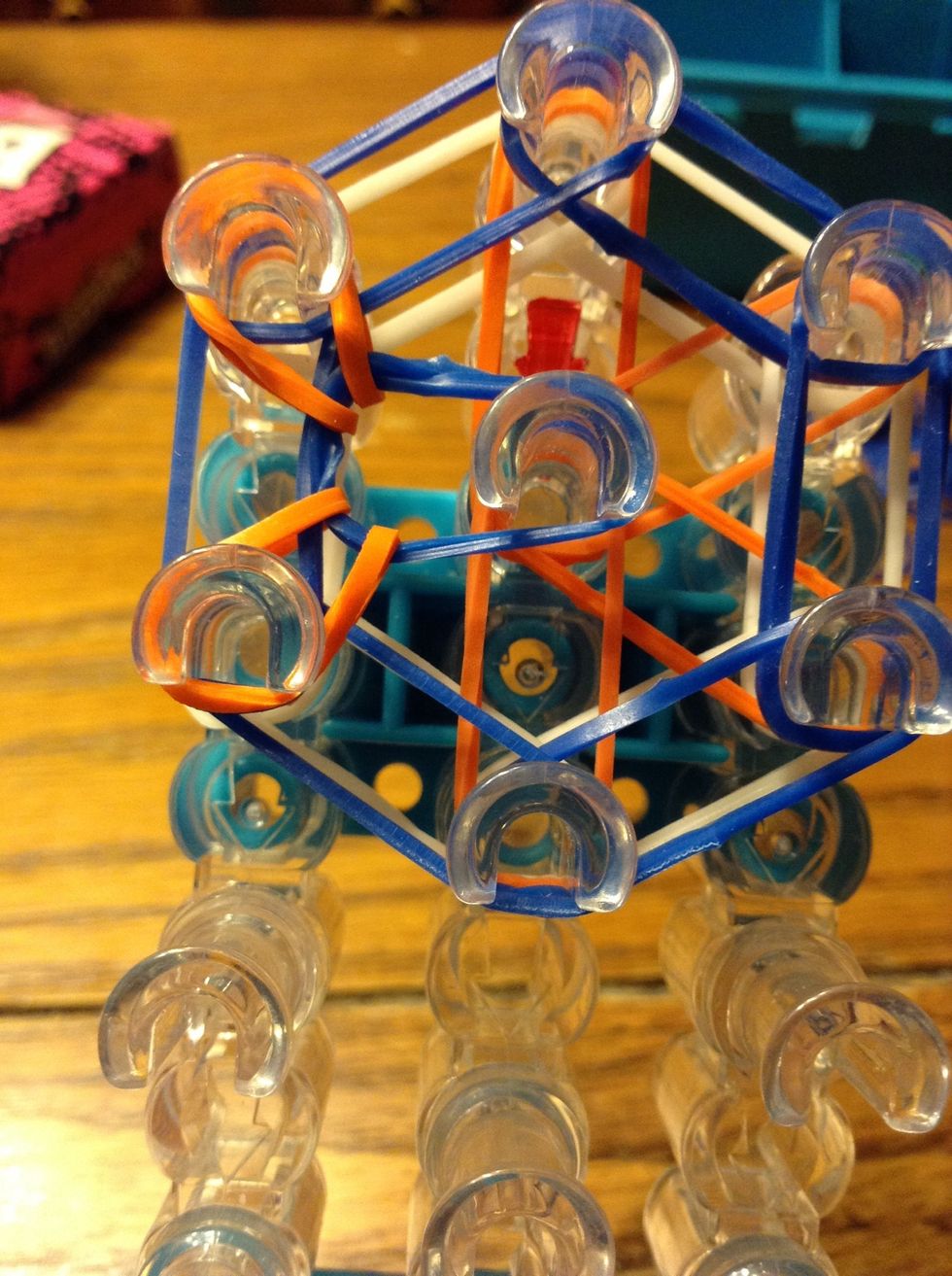 Like so. Continue taking the top orange bands on the middle peg and looping them on the outer pegs counterclockwise.