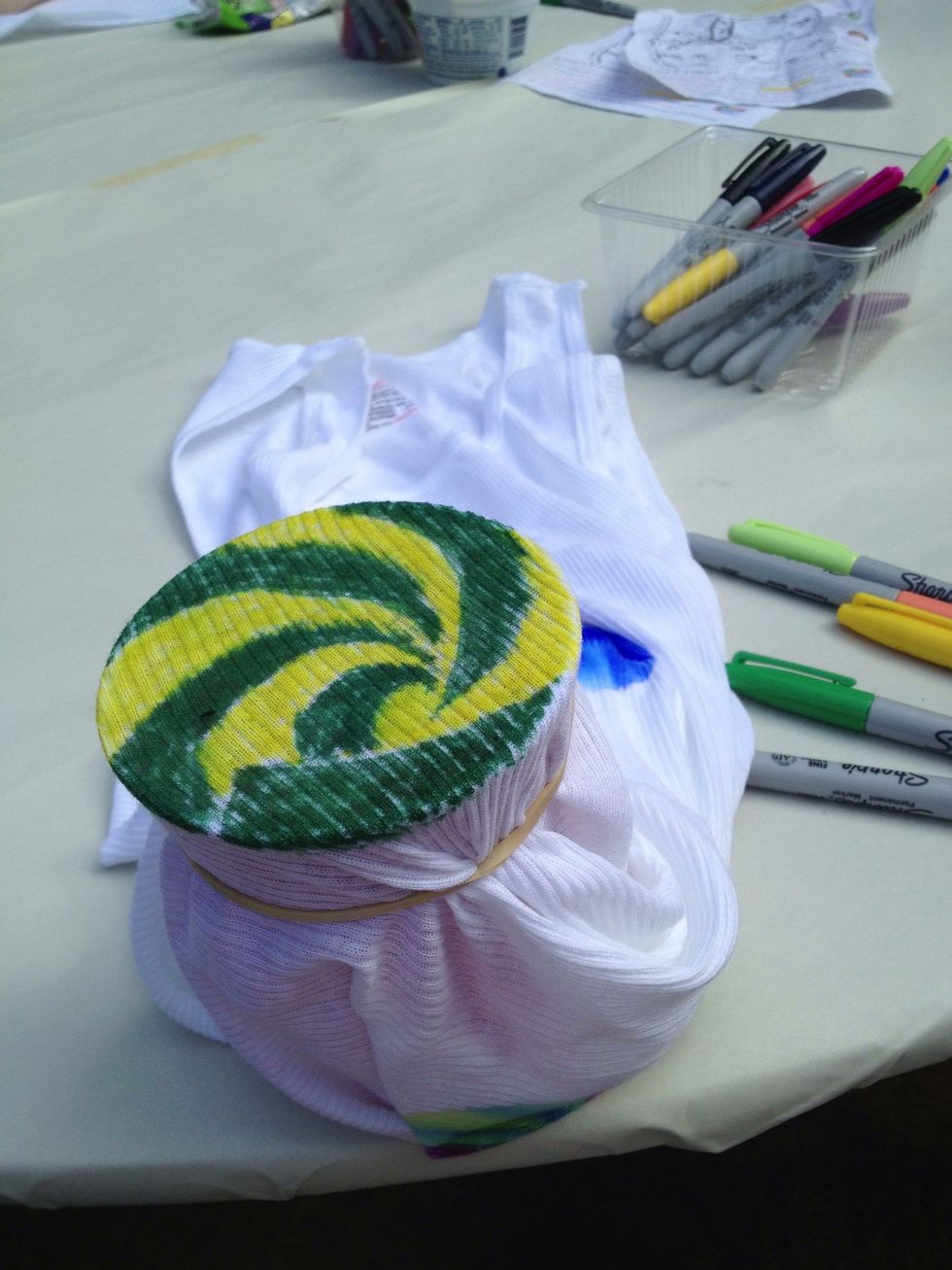 Like this.  The cup is inside the shirt. Now use sharpies to draw your desired designs and pictures on the shirt. Small detail is not recommended as the colors will bleed.