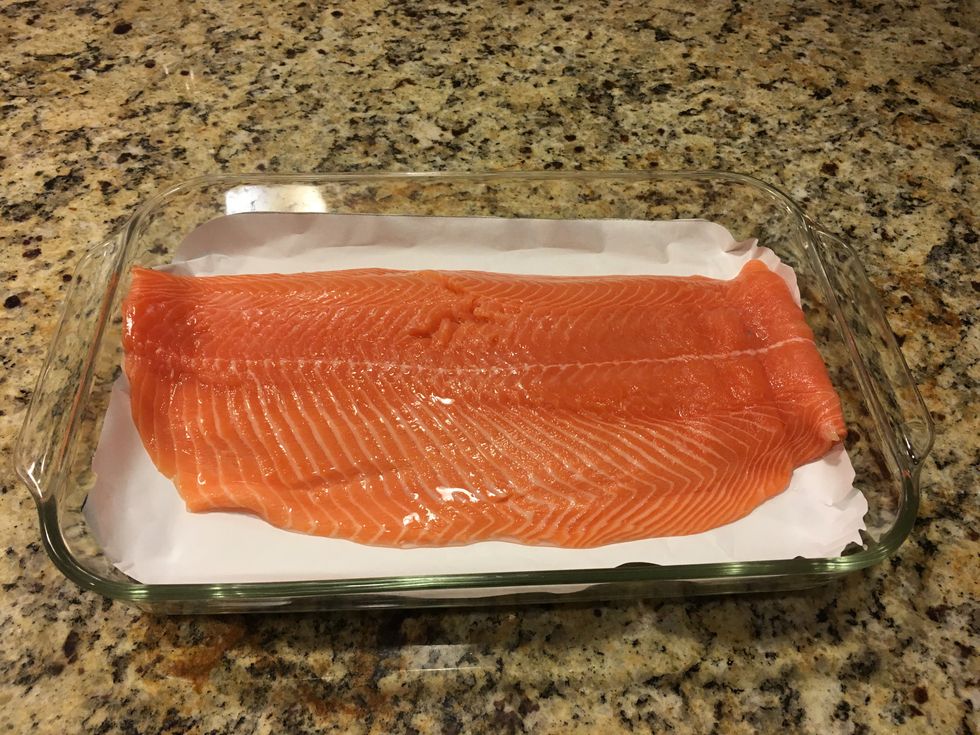 Line a baking tray with parchment paper and place the salmon fillet in it.