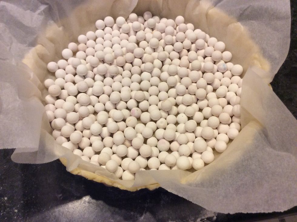 Line pastry with baking paper and fill with pie weights.