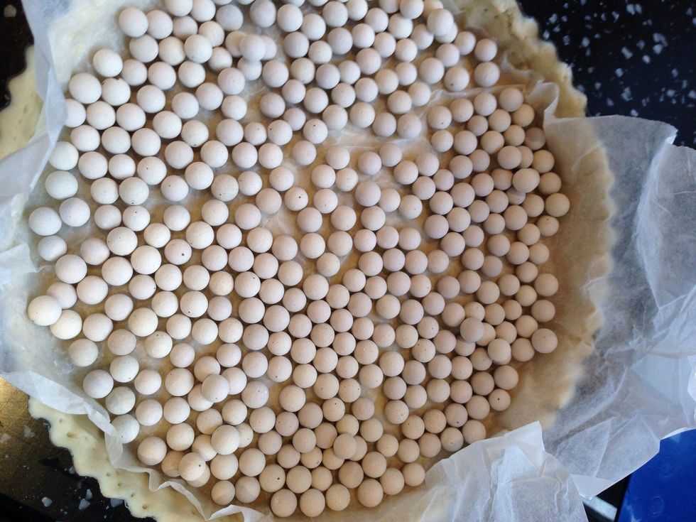line the tart case with a large circle of greaseproof paper or foil, then fill with baking beans. Blind-bake the tart for 20 mins