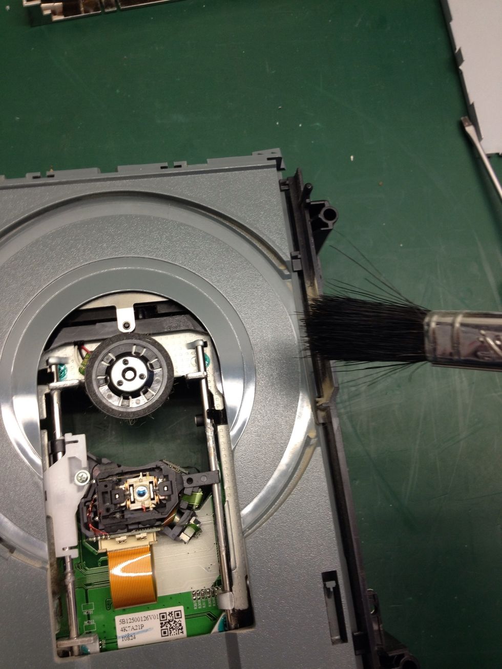 Locate dust and brush it AWAY from the laser. Do not brush the laser itself.