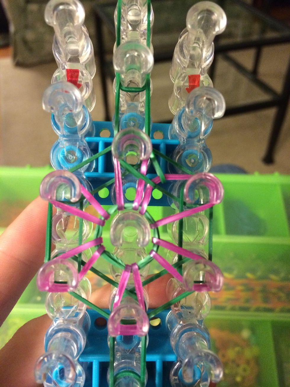 Loop it to the center left. Reach in the next peg and grab the next band.