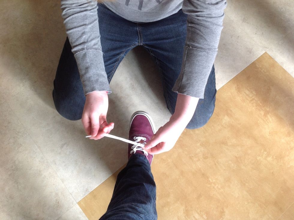 Loop one of the laces under the other.