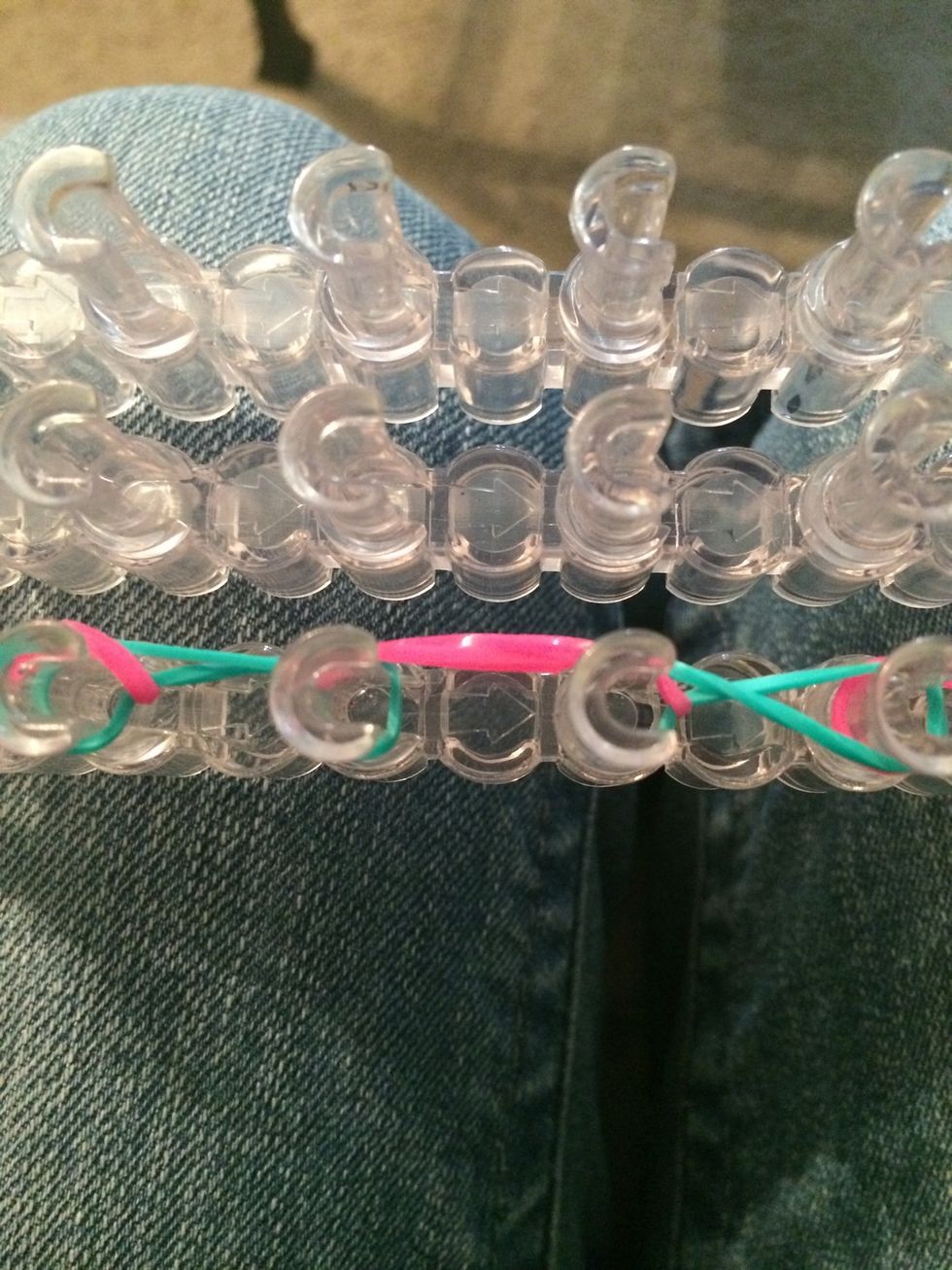 Loop over the next pink rubber band over the 3rd and 4th pegs