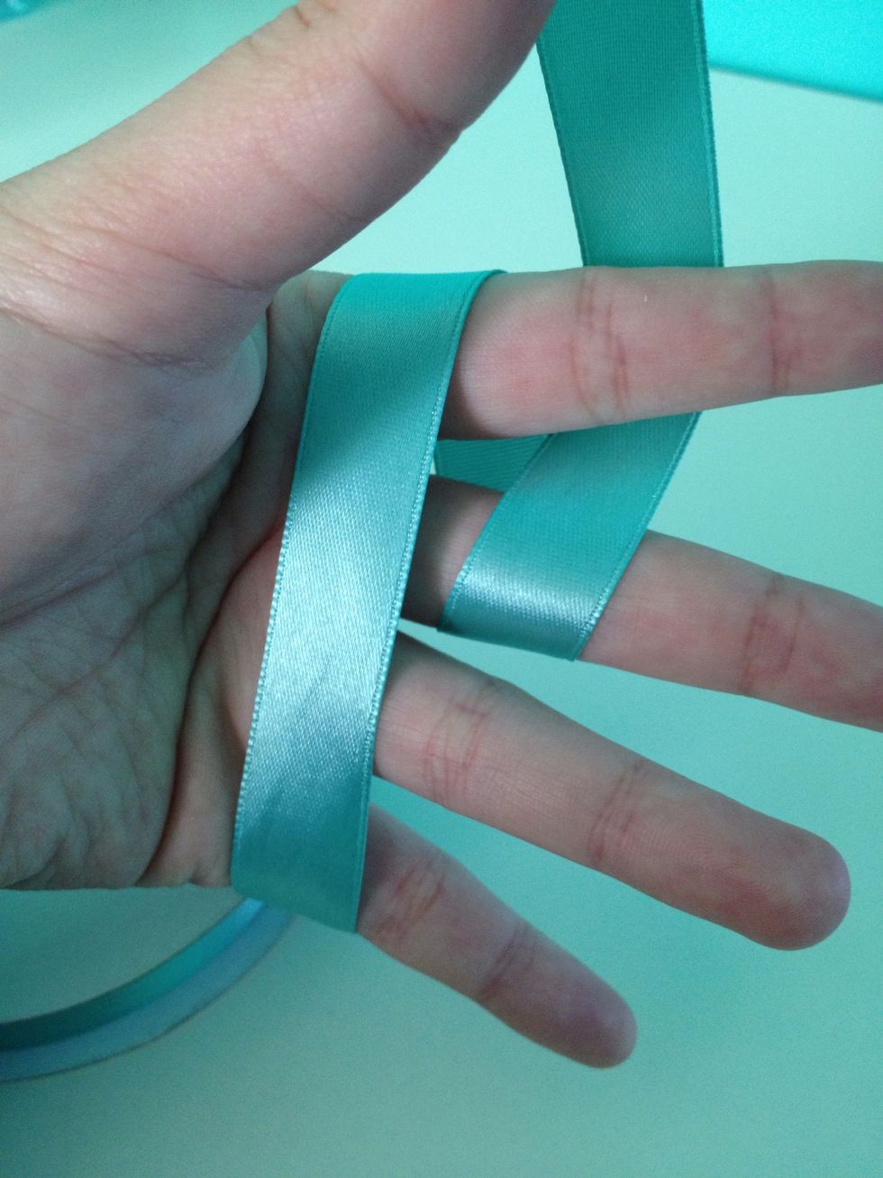 Loop the ribbon on the outer right side over your second finger and under your first.