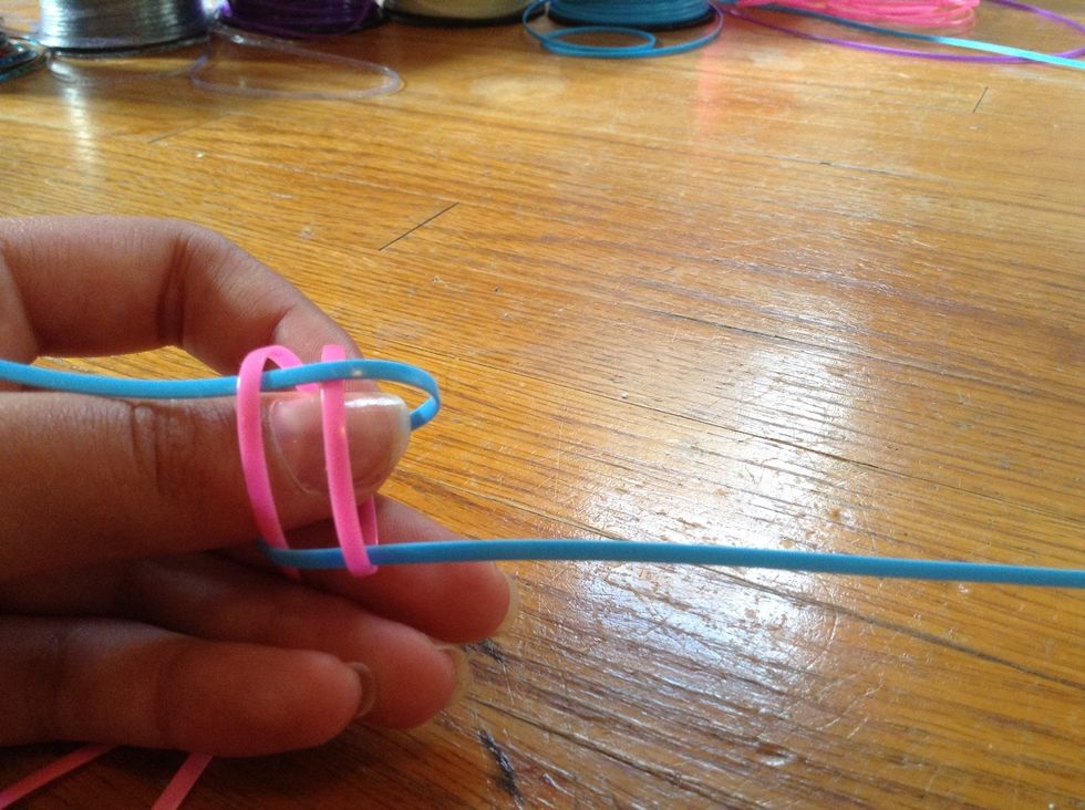 Loop the string on the right over the right pink and under the left pink. Do the same looping on the left, over the left loop, under the right.