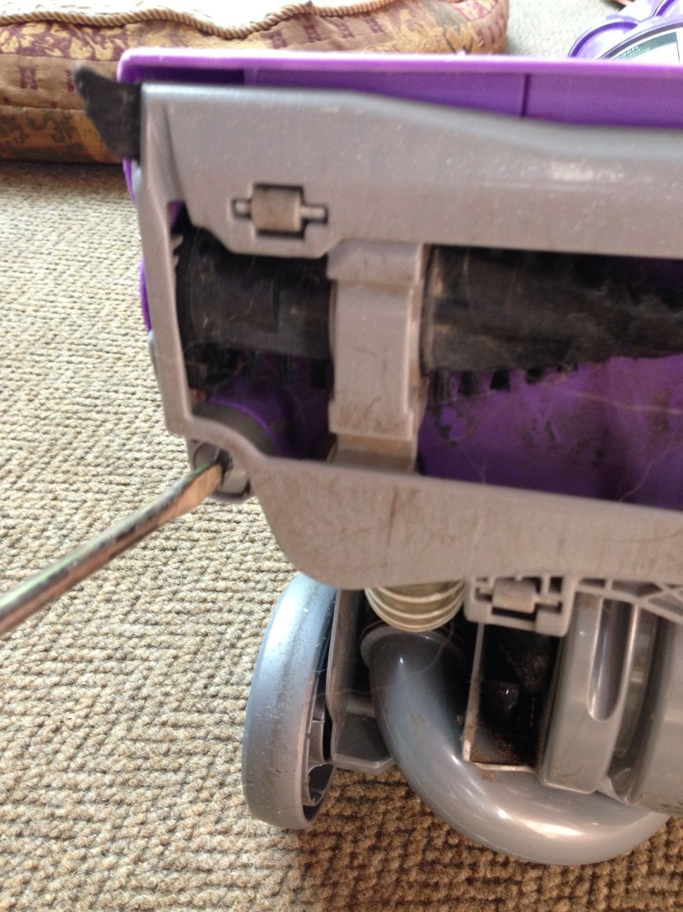 Loosen three plastic screws holding in the beater bar with the flat screwdriver or a quarter. Only a half turn