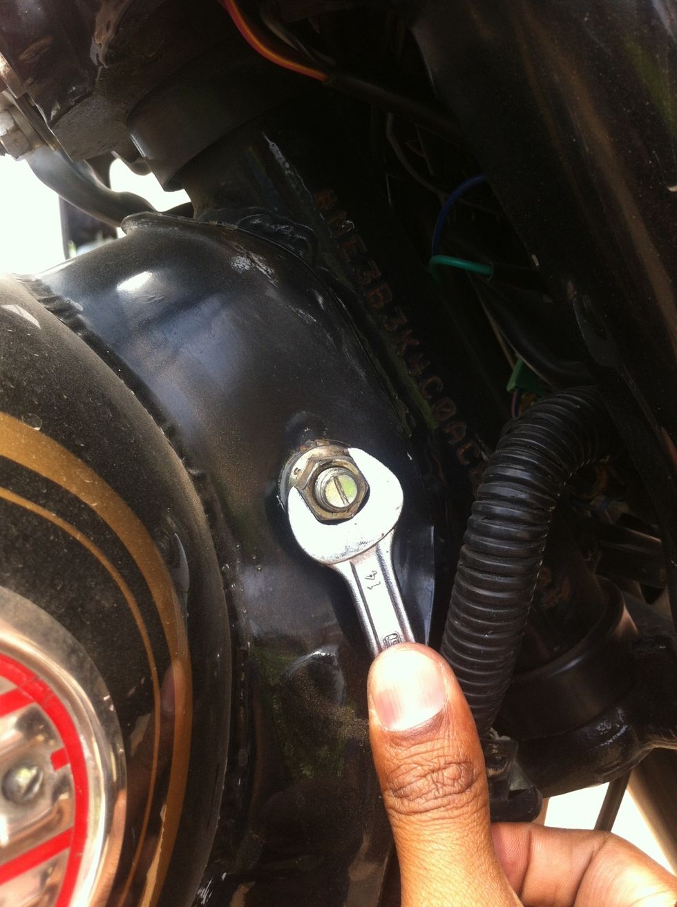 Loosening the front nut with a 14mm spanner while holding the bolt with a same size spanner on the other side.