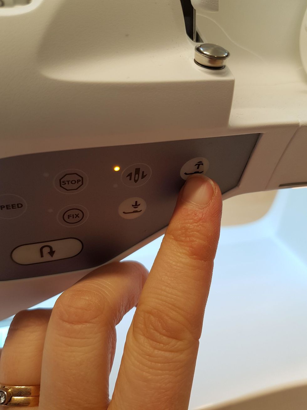 Lyft pressarfoten genom att trycka p\u00e5 den h\u00e4r knappen.