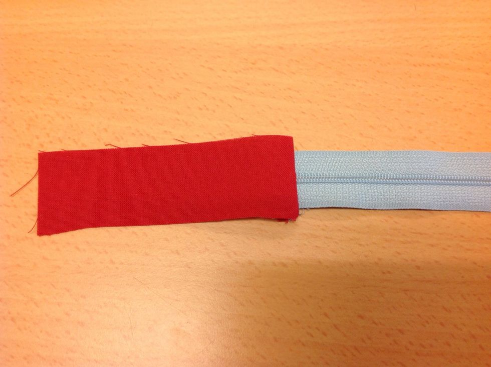 M\u00e4t till en dragkedja som \u00e4r ett par cm kortare \u00e4n tygets bredd. sy fast en tygbit i varje \u00e4nde av dragkedjan s\u00e5 det blir ett stopp.