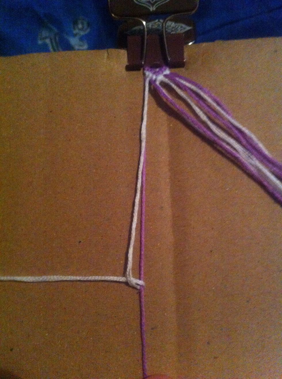 Make a backward 4 knot with the second string (white) over the first string (purple).