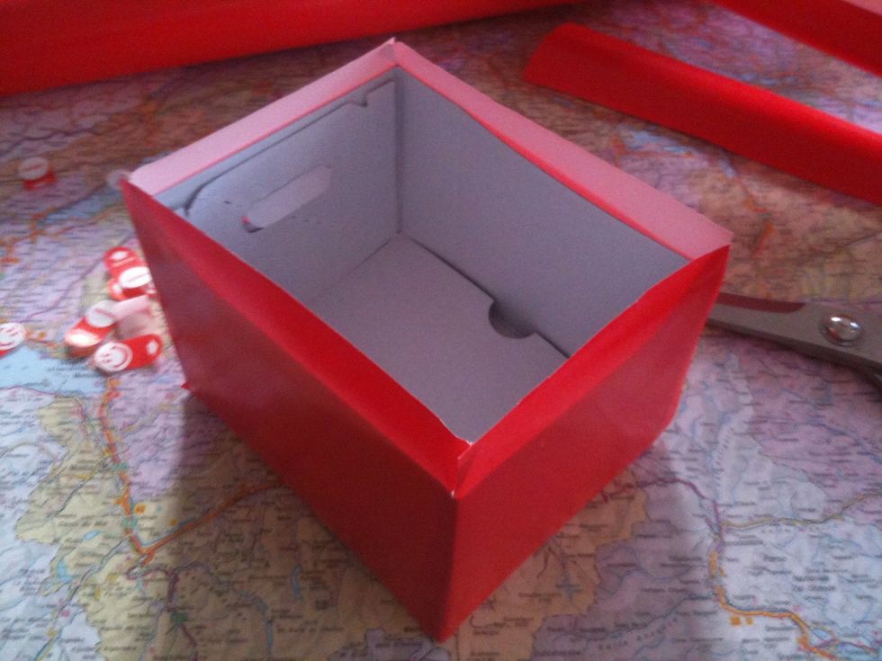 make a band with the red paper and stick it around the box