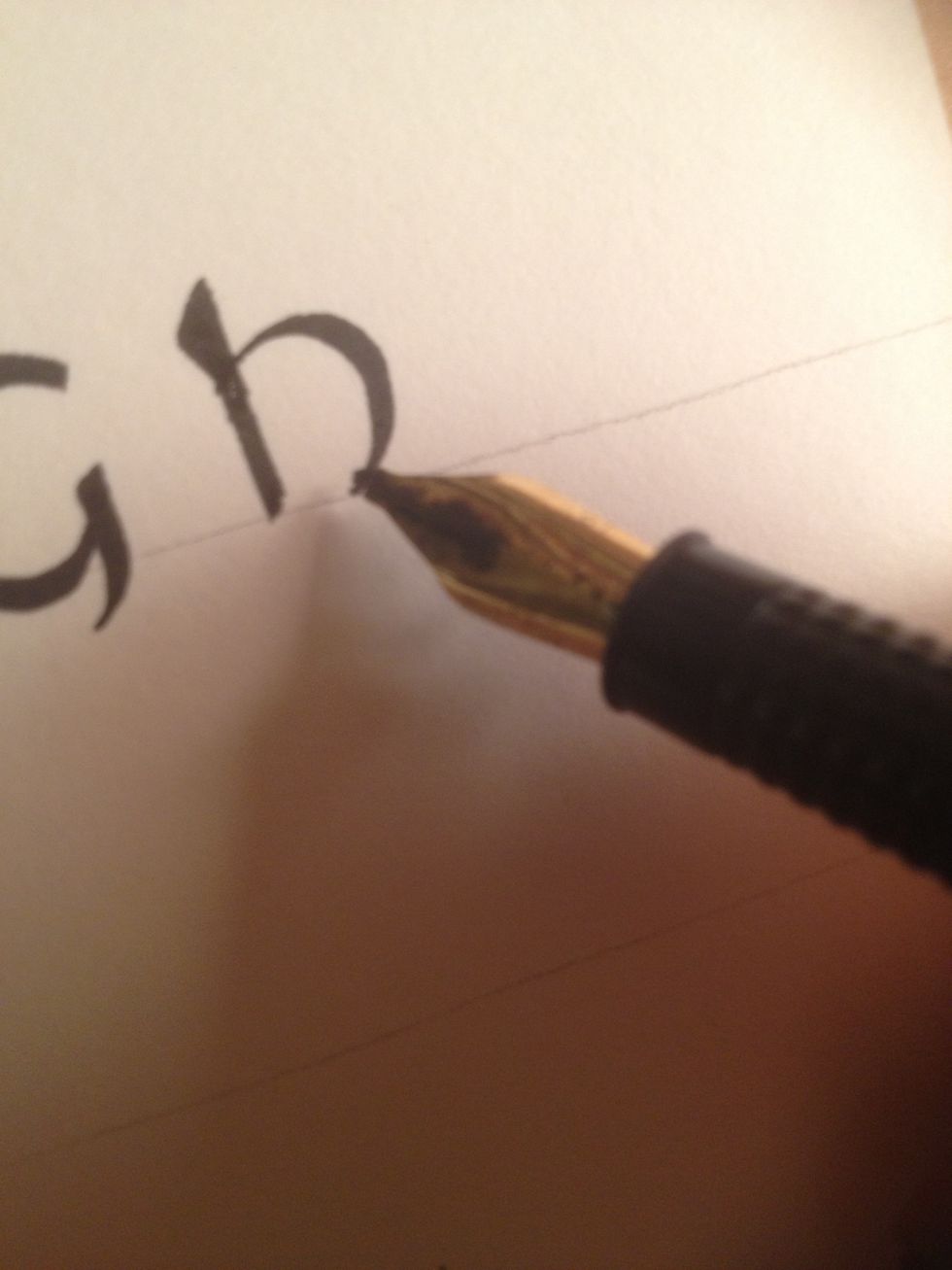 Make a circular stroke terminating at the bottom line; if your nib is angled correctly, the stroke should be thin at both ends and thick in the middle.