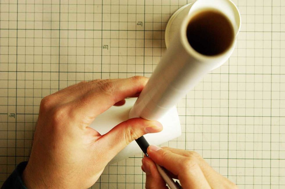 Make a hole in the paper cups with a utility knife.