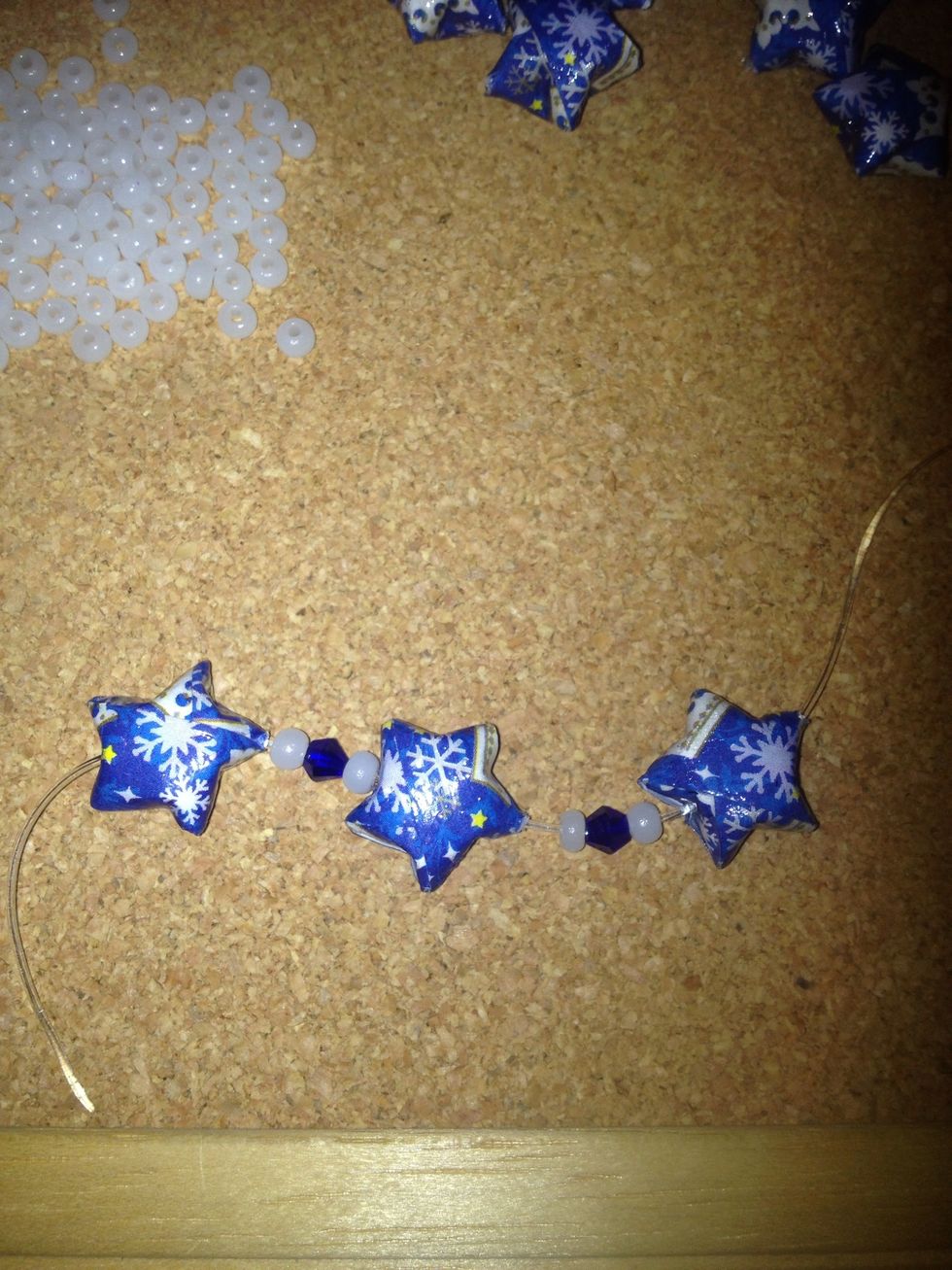Make any bead combo that you like. I used a seed bead, crystal, seed bead combo. Put the needle back on the cord and add another star. Repeat your bead combo and add another star.