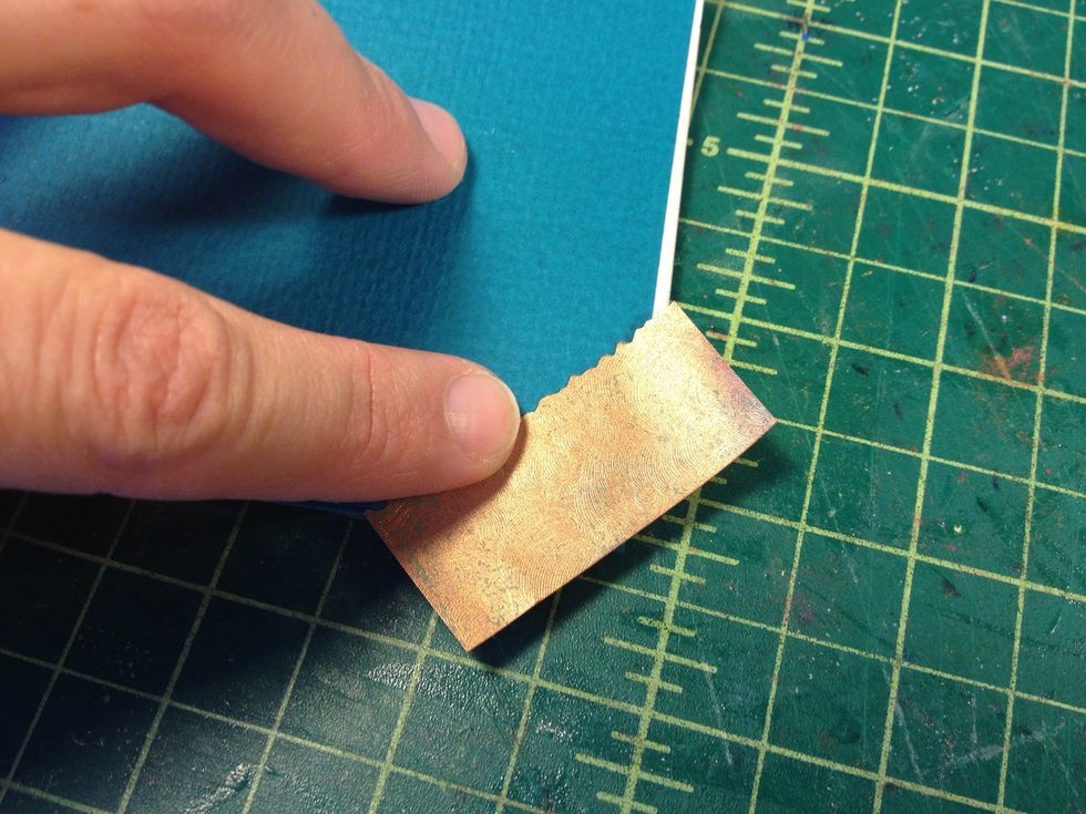 Make corner reinforcement details. Cut and "edge" some small pieces of the same paper. Add glue and stick to the corners as shown.