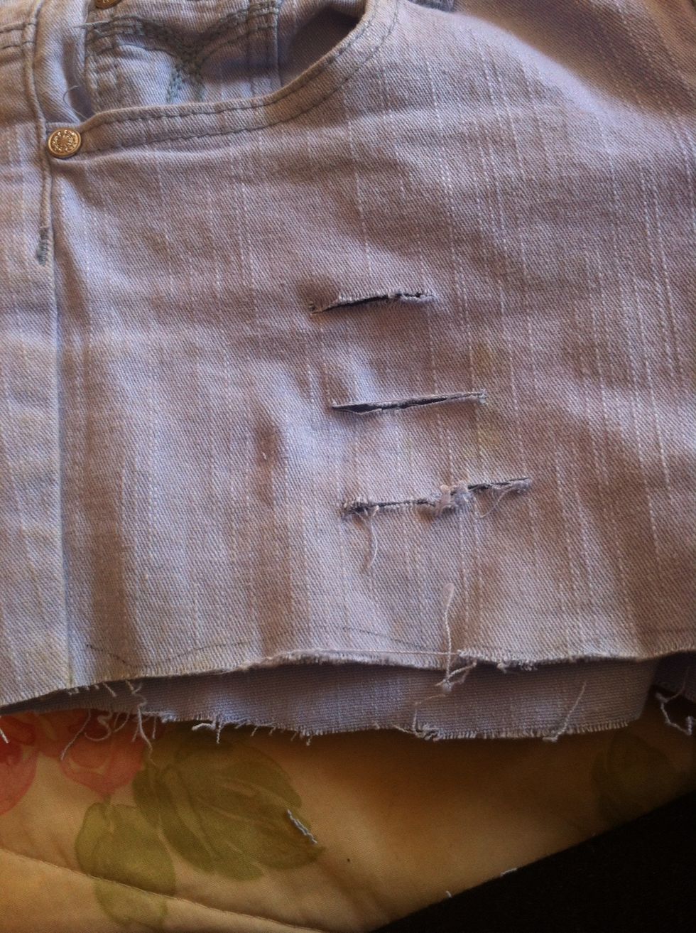 Make small cut in the face of the shorts and fray the edges