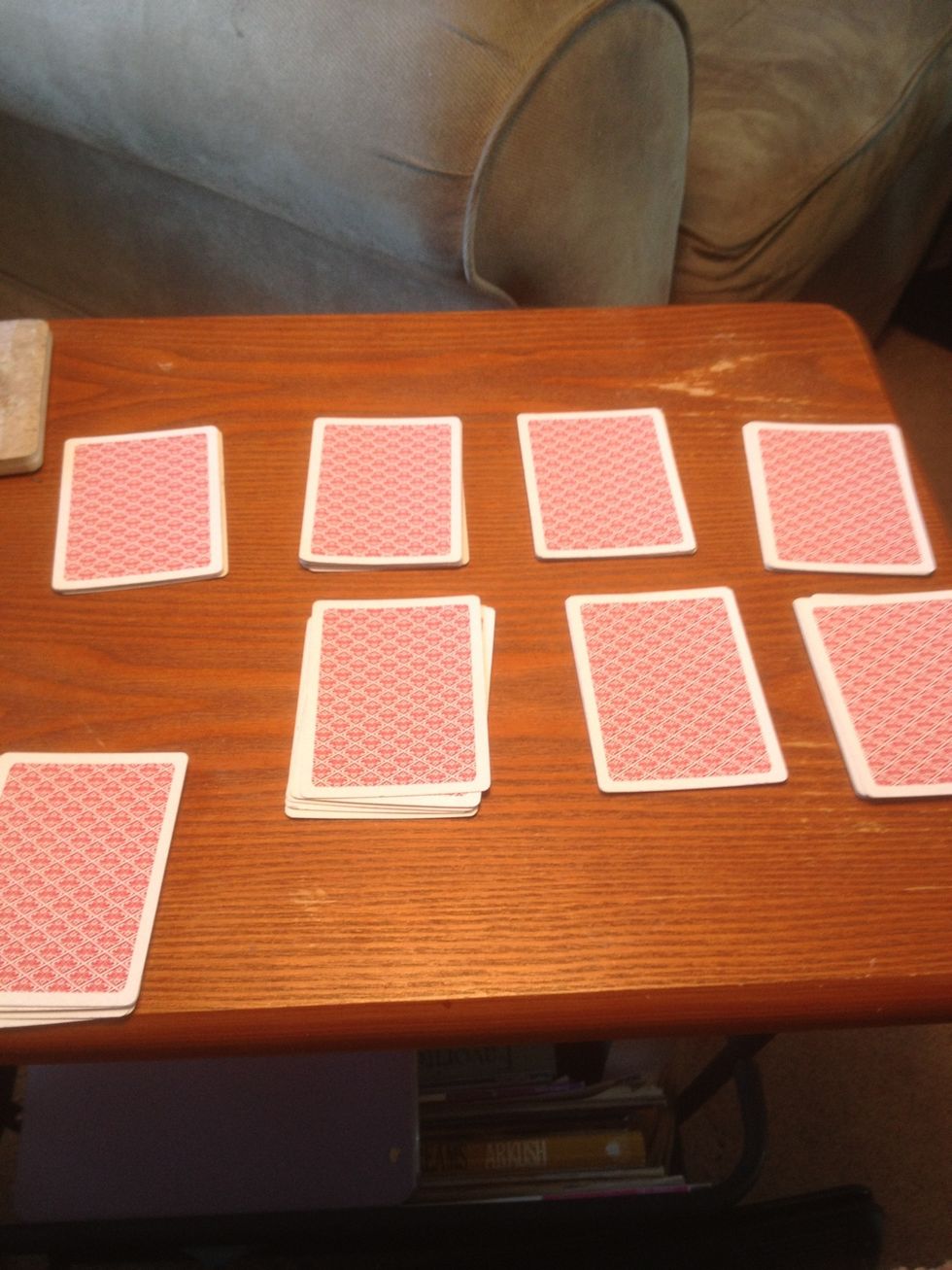 Make sure all stacks face down, making note where your leftovers are, mine are bottom left. However many stacks are left, ask someone to eliminate any number of random stacks so only 3 piles remain.