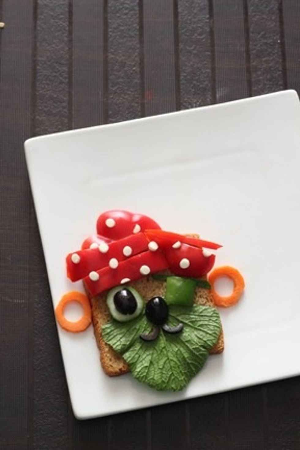 Make the eye with a small cucumber slice ,topped with olive , place the capsicum piece as eyepatch and carrot ear rings. Finally  place the olive nose and moustache. Ahoy Matey the pirate is all done.