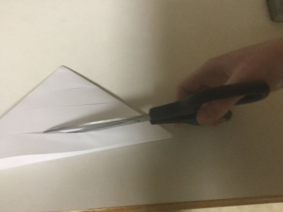Make three cuts into one side of each triangle. You should not cut all the way through the triangles. Instead, stop cutting about 1 1/2 inches from the end of the paper.