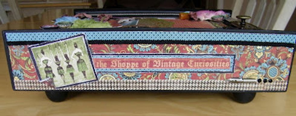 Making sure to cover the sides with different pieces of the Olde Curiosity Shoppe paper, ribbon, metals, etc and adding the black ball legs