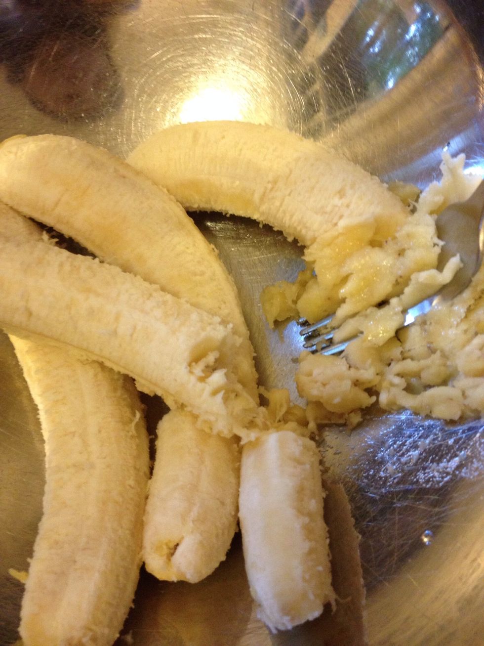 Mash four bananas with a fork in a large mixing bowl.