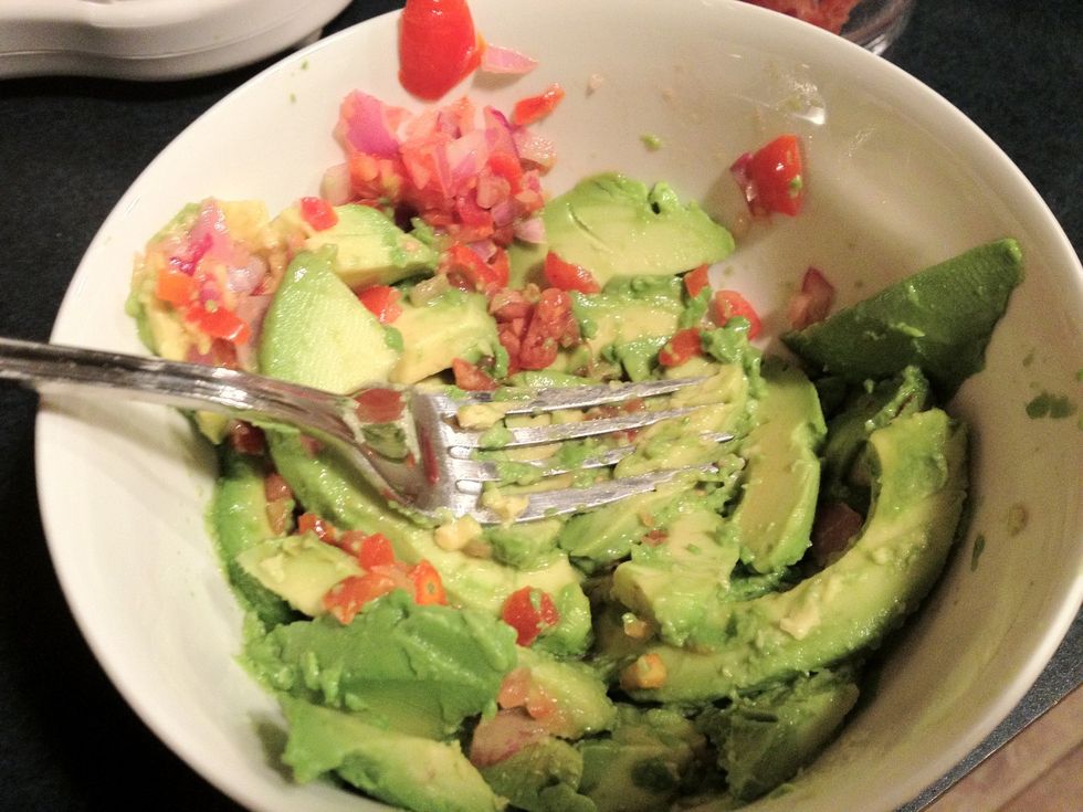 Mash up the avocado into coarse pieces with a fork. No need to overdo it. (I added some of the onion-tomato mix before mashing but it may be easier to mash the avocados alone)