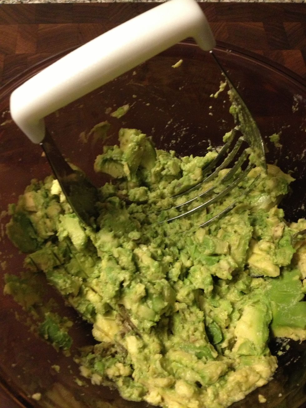 Mash up the avocados. I use a pastry cutter because it leaves a couple of chunks which give the guacamole some extra texture.